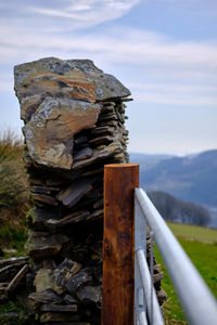 Close-up of old rusty stack on field against sky