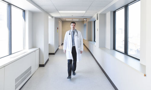 Doctor in white coat walking down the hallway in a hospital.
