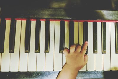 Cropped hand of baby playing piano at home