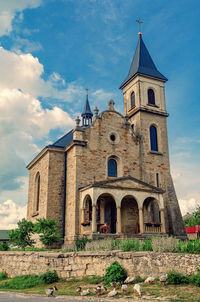 Goslings graze near church. rural landscape with stone church on background of cloudy sky.