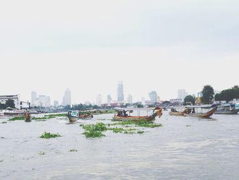 Scenic view of river by cityscape against sky