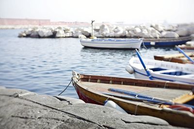 Boats moored at harbor against sky