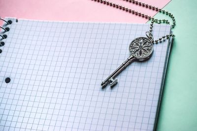 High angle view of key locket on spiral notebook on table