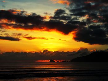 Scenic view of sea against dramatic sky during sunset