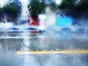 Cars on street seen through wet glass window