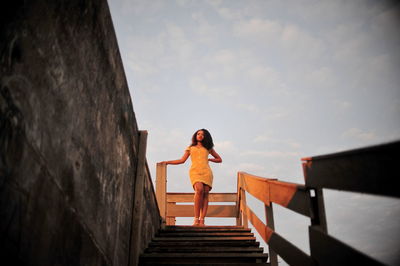 Woman standing on staircase against sky