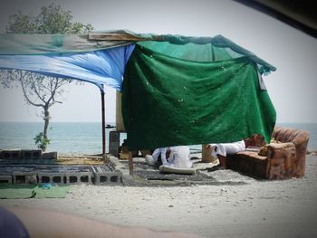 Lounge chairs and table at beach against sky