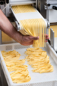 Cropped hand of man preparing spaghetti in factory