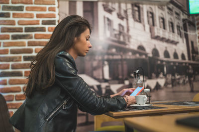 Side view of a young woman using smart phone