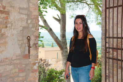  woman in front of panorama of san gimignano, medieval tuscan city in stone and red bricks in italy