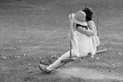 Monochrome image of happy couple sitting side by side on a wooden swing in the garden