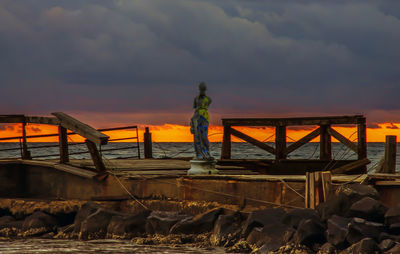 Man standing on beach against sky during sunset