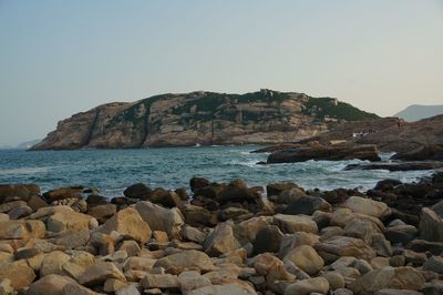 Rocks on sea shore against clear sky