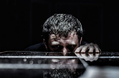 Portrait of man by table against black background