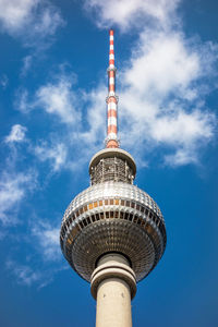 Low angle view of communications tower against cloudy sky