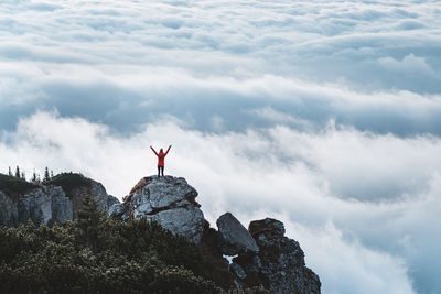 Man standing on rock against sky