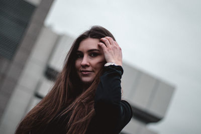 Portrait of young woman standing against wall