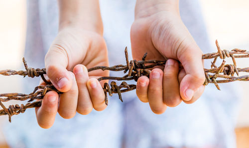 Midsection of woman holding barbed wire