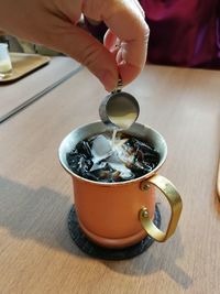 High angle view of hand holding tea cup on table