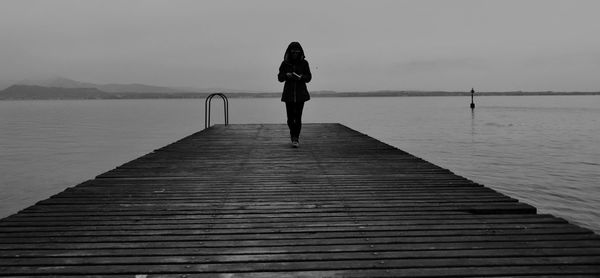 Rear view of woman standing on pier