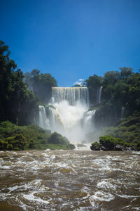 Scenic view of waterfall in forest against sky