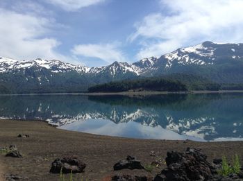 Scenic view of lake by snowcapped mountains against sky