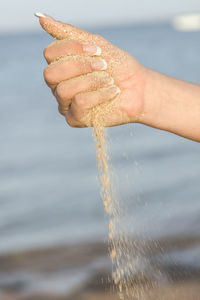 Cropped image of sand falling out of closed fist