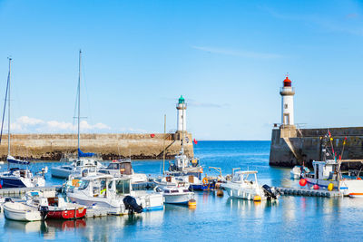 Sailboats moored at harbor against sky