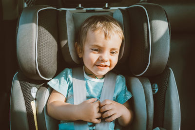 Cute baby boy sitting in car safety seat