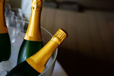 Closeup of champagne in wine chiller with defocusses champagne glasses and black background