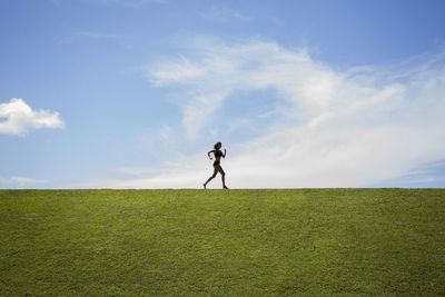 Rear view of man standing on field against sky