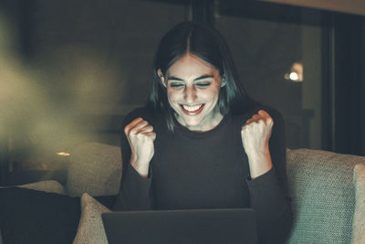Portrait of young woman sitting on sofa at home