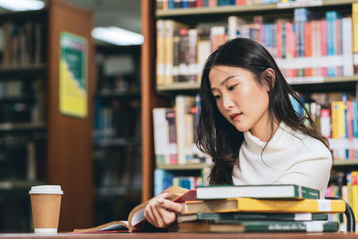 Young woman reading book on table