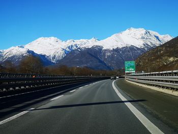 Road leading towards snowcapped mountains against sky