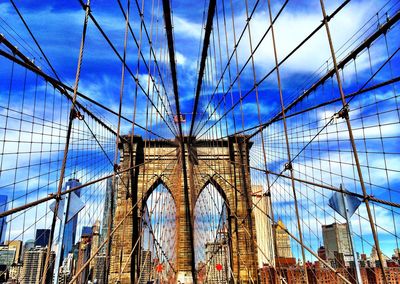 Low angle view of suspension bridge against cloudy sky