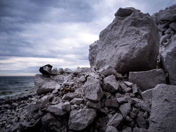 Close-up of rocks against cloudy sky at beach