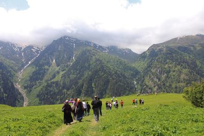 Group of people on field against mountain range