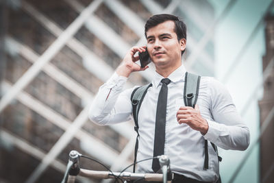 Young man holding camera while standing outdoors