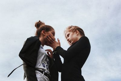 Low angle view of lesbian couple standing against sky