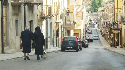 Rear view of people walking on road in city