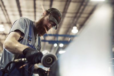 Low angle view of worker using welding machine in steel factory