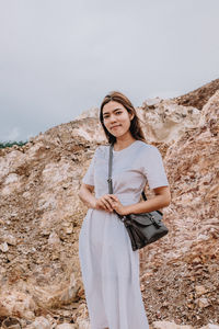 Portrait of smiling young woman standing against rock formations