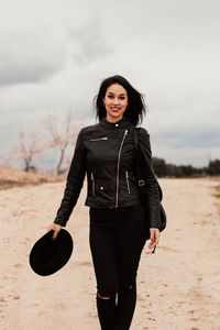 Portrait of smiling woman standing on land against sky