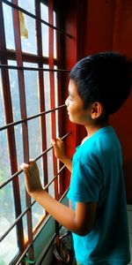 Side view of boy standing against window