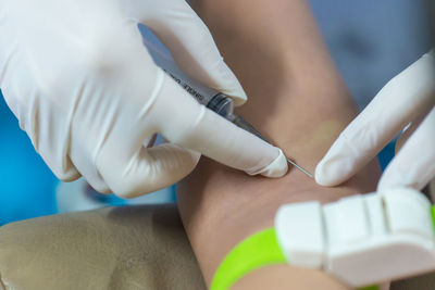 Cropped hand of doctor injecting patient in hospital