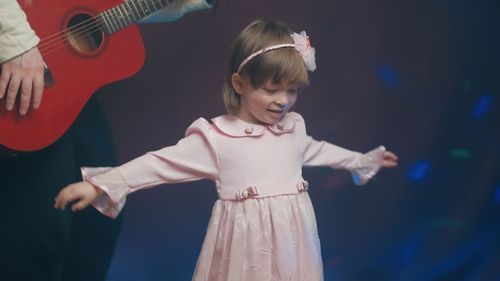 Portrait of cute girl playing with toy while standing against black background