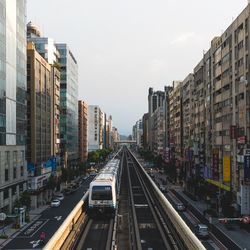 Traffic on road amidst buildings in city against sky