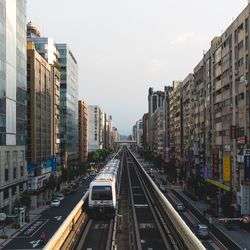 Traffic on road amidst buildings in city against sky