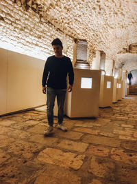 Full length portrait of young man standing against wall