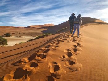 Rear view of people on desert against sky